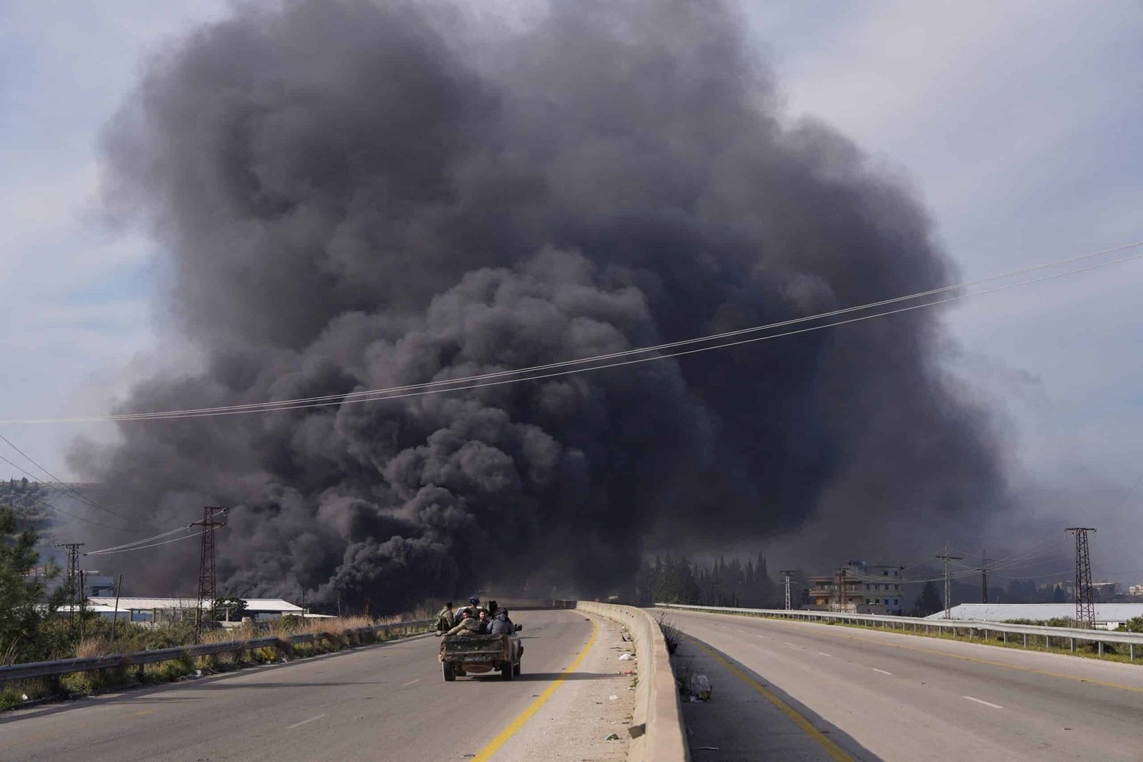 Photo: The smoke rises while the members of the Syrian forces travel in a vehicle in Latakia